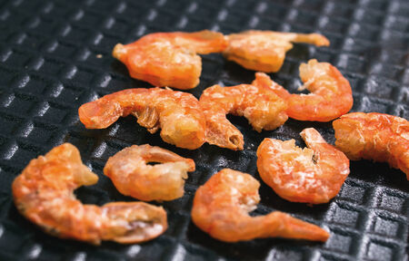 Dry small shrimps on black foam plateの写真素材