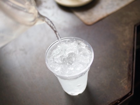 pouring fresh water to glass of iceの写真素材