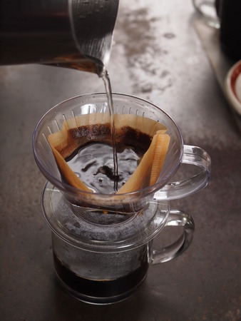 Cup of Dripping fresh hot coffee, pouring hot water to blended coffee on paper filterの写真素材