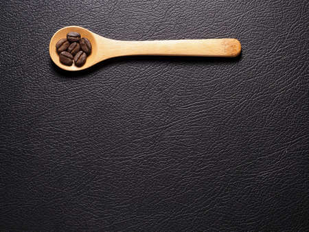 Coffee crop beans on bamboo spoon and leather texture backgroundの写真素材