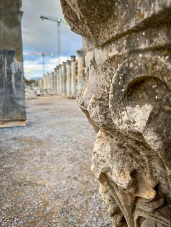 Row of fluted ancient columns stretches along the gravel-strewn Curetes Street in Ephesus, with a...