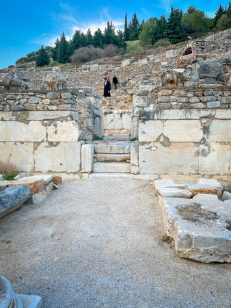 Weathered limestone walls with protruding winged sphinx guardians rise dramatically around two...
