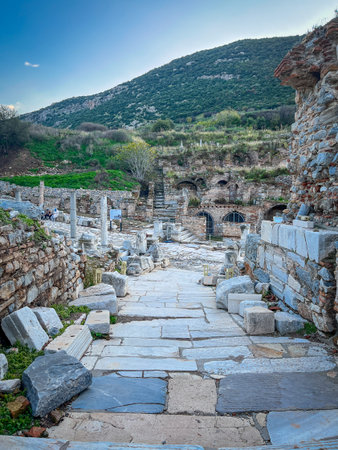 Weathered slabs form a rugged pathway flanked by toppled white marble column sections and rugged...