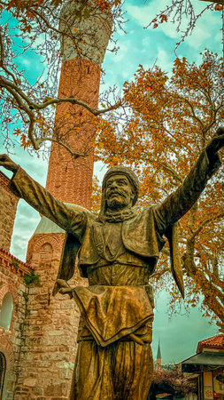 Pergamon, the illustrious capital of the Hellenistic Attalid Dynasty under kings Eumenes II and Attalos II in the 2nd century BC, boasts enduring ruins intertwined with Ottoman-era monuments. High-resolution imagery reveals sharp details, vivid autumnal orange foliage, and dynamic cloudy skies illuminating the textured bronze figure and brick architecture.の写真素材