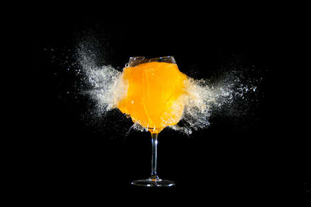 Glass with orange juice explosions at the black backgroundの写真素材