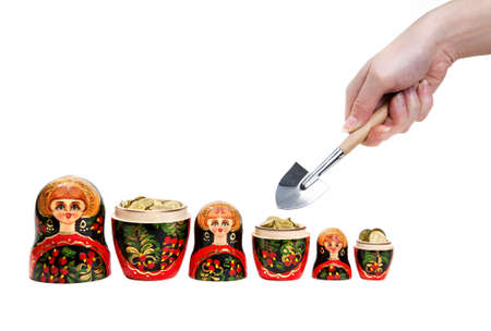 Three Matryoshkas full of coins and hand holding shovel at white backgroundの写真素材