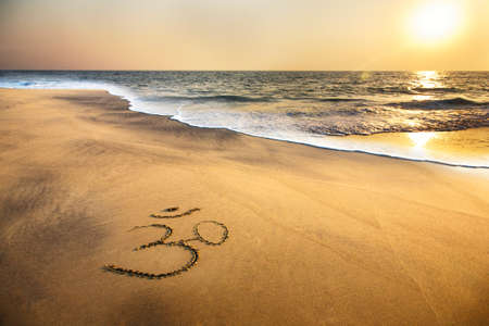 Om symbol on the sand at the beach near the ocean