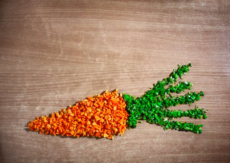 Carrot  from chopped raw carrot and leaves from green beans on the textured table represent pure vegetarian cuisine. Free space for textの写真素材