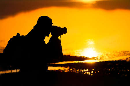 Photographer silhouette shooting sea outdoors at sunset backgroundの写真素材