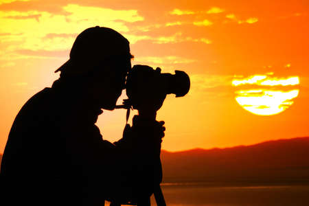 Photographer silhouette shooting sea outdoors at sunset backgroundの写真素材