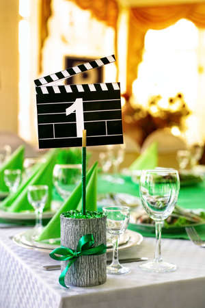 Wedding table served in green colors in movie style with clapboard and number one on it の写真素材