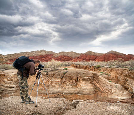 Photographer shooting drought Aktau mountains at dramatic sky background in altyn emel national park in Kazakhstanの写真素材