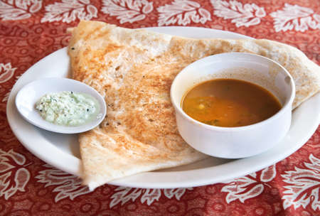 Indian traditional vegetarian masala dosa with potato inside, sambar and coconut chutney nearby at Indian restaurantの写真素材