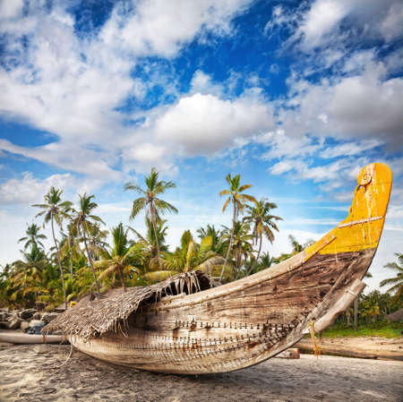 Fishing boat on the beach at dramatic cloudy sky at palm trees background  の写真素材
