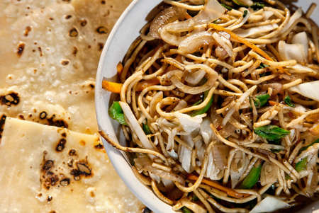 Vegetarian noodles and butter naan on the table in restaurant in Varkala, Kerala, Indiaの写真素材