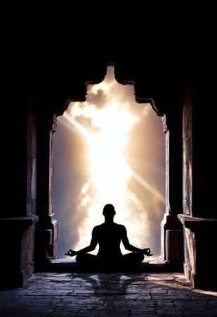 Yoga meditation in lotus pose by man silhouette in old temple arch at dramatic sky background. Free space for text Yoga meditation in lotus pose by man silhouette in old temple arch at dramatic sky background. Free space for text