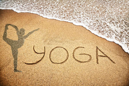 Yoga title with man doing yoga on the sand beach near the oceanの写真素材