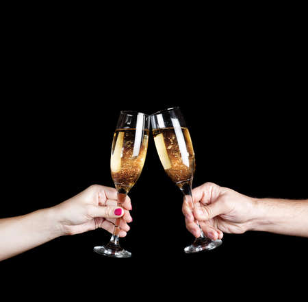 Couple holding two glasses with champagne at black background. Free space for your textの写真素材