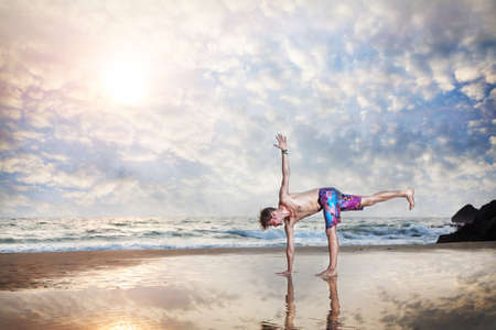 Yoga by man on the beach with reflection on the sand near the ocean in India