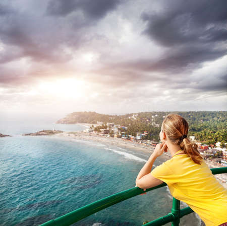 Woman looking to the beach and ocean from Lighthouse at overcast sky in Kovalam, Kerala, India  の写真素材