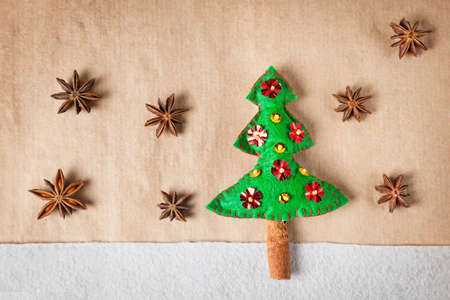 Handmade decorated Christmas tree from felt and star anise around on brown paper の写真素材