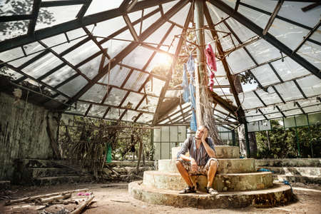 Man sitting in ruined greenhouse in Botanical garden, Puducherry, Indiaのeditorial素材