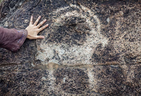  Woman touching the stone with ancient petroglyph of goat in museum of Kyrgyzstan の写真素材