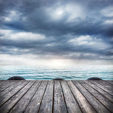 Pier with wooden floor at dramatic overcast sky backgroundの写真素材