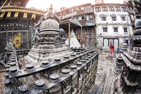 THAMEL, KATHMANDU, NEPAL - APRIL 3, 2014: Woman in red sweeping the yard in Seto Machhendranath templeのeditorial素材