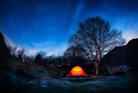 Orange tent in the mountain valley at blue night sky with stars in Kazakhstanの写真素材