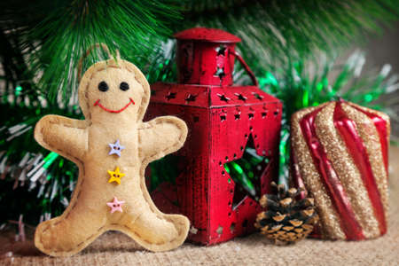 Gingerbread toy from felt near the red lantern and candle near Christmas tree