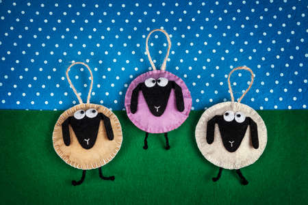 Three sheep toys from felt on green and blue background