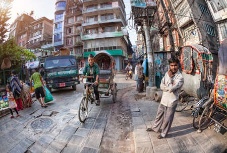 THAMEL, KATHMANDU, NEPAL - APRIL 3, 2014: Rickshaws driving by the street near vegetable market at...