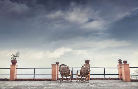 Two wooden chairs on the hotel balcony with cloudy sky viewの写真素材