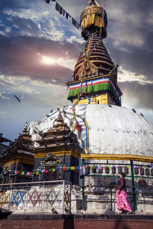 THAMEL, KATHMANDU, NEPAL - APRIL 3, 2014: Woman in pink dress rolling prayer wheels and doing kora...