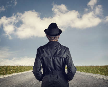 Man in black hat on the road at blue cloudy sky backgroundの写真素材