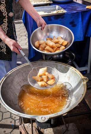 Woman frying Baursaks national kazakh food in big pot with hot oil at Nauryz celebrationの写真素材