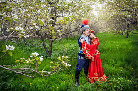 Couple in Kazakh costume in Spring Blooming apple garden of Almaty, Kazakhstan, Central Asiaの写真素材