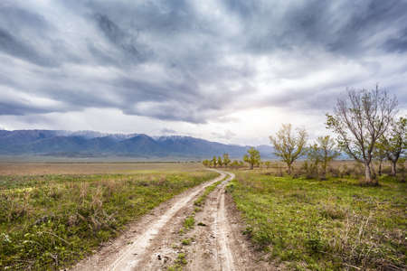 Road near Alakol Lake and mountain scenery at dramatic overcast sky in Kazakhstan, central Asiaの写真素材