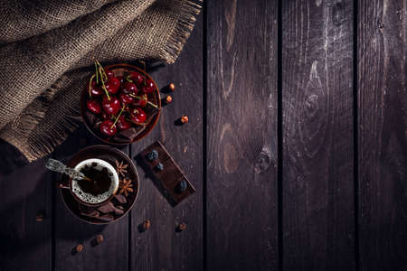 Coffee cup, dark chocolate and cherries on the wooden tableの写真素材