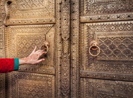 Woman hand with henna painting opening golden door in City Palace of Jaipur, Rajasthan, Indiaの写真素材