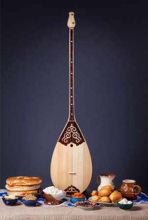 Dombra Kazakh instrument and Asian dishes on the table at grey backgroundの写真素材