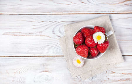 Strawberry in the cup with white flower on wooden tableの写真素材