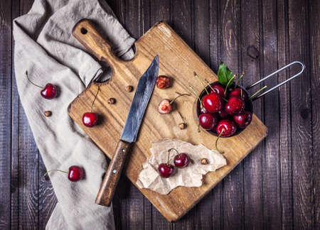 Cherry on the cutting board with knife on wooden table in the kitchenの写真素材