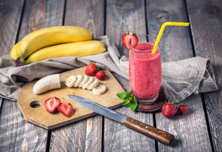 Banana and strawberry smoothie on wooden backgroundの写真素材