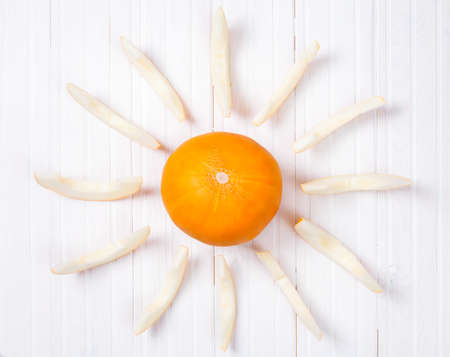 Yellow melon in shape of sun on white wooden backgroundの写真素材