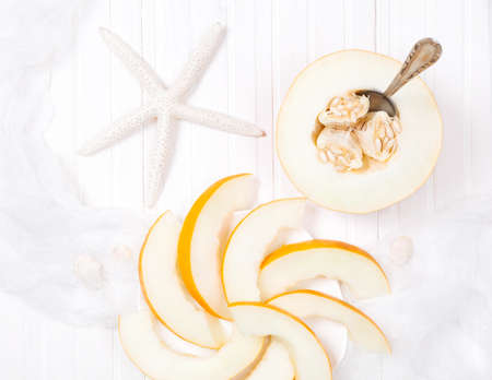Yellow melon and starfish on white wooden backgroundの写真素材