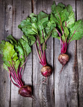 Raw beetroot with green leaves on wooden background