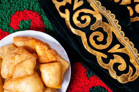 Asian bread baursak and ethnic hat on the carpet in yurtaの写真素材