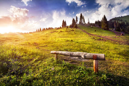 Wooden bench in the mountains at sunrise cloudy sky in Kok Zhailau, Kazakhstan, central Asiaの写真素材